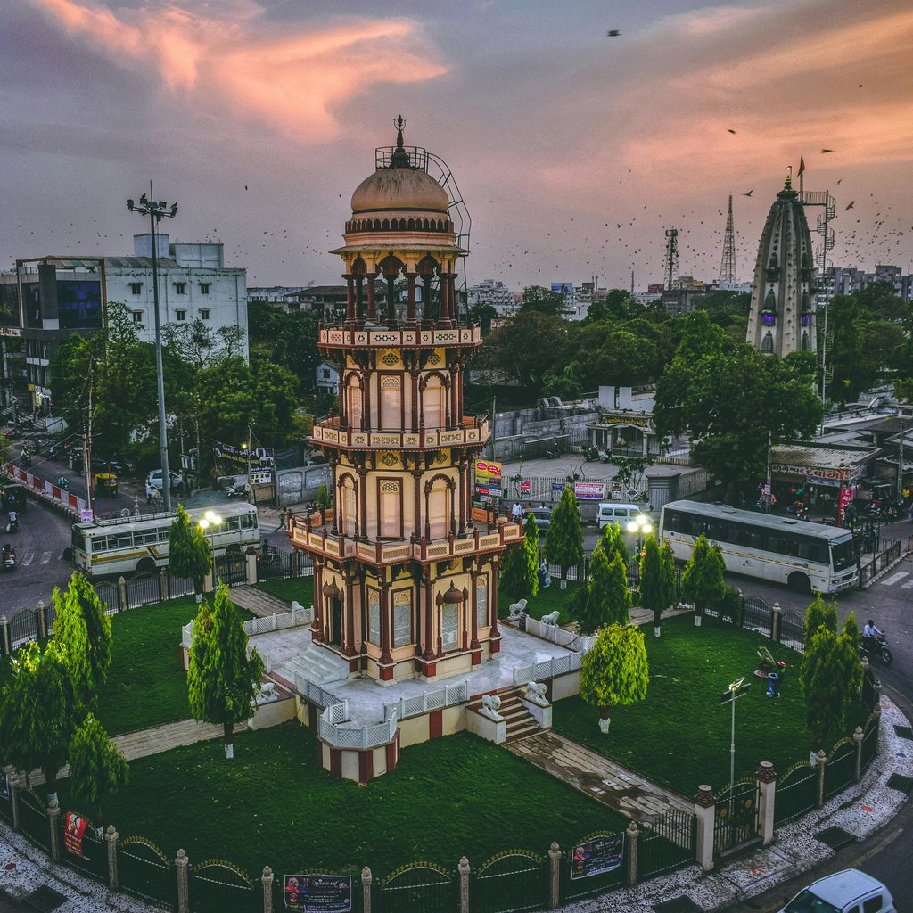Aerial view of a historic tower in Ahmedabad, India at dusk surrounded by urban cityscape.