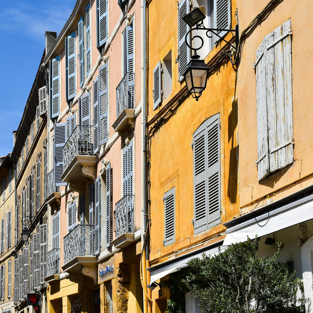 Colorful historic buildings on a sunny street in Aix-en-Provence, showcasing French architecture.