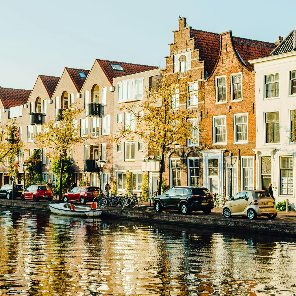Bright autumn day in Amsterdam with reflections of canal houses and colorful leaves.