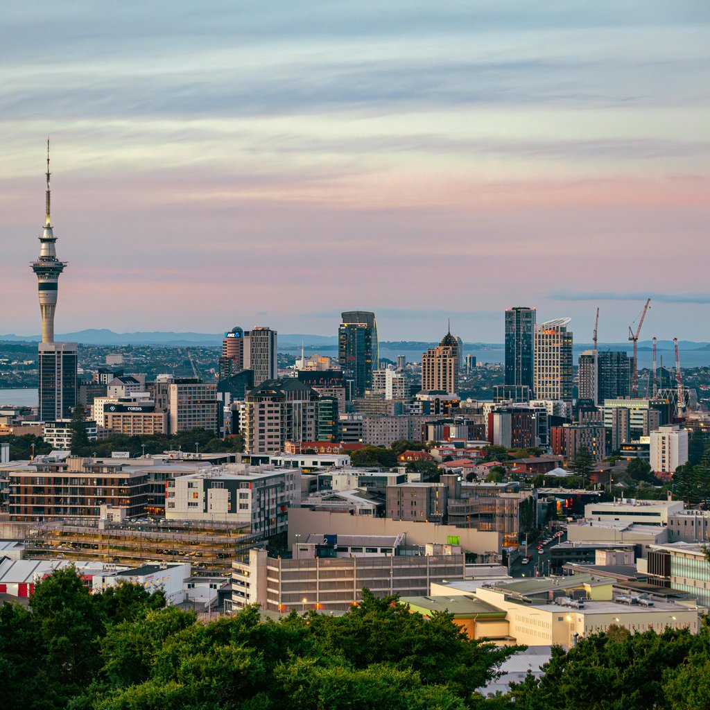 Captivating view of Auckland's skyline at dusk featuring the iconic Sky Tower under a colorful sky.