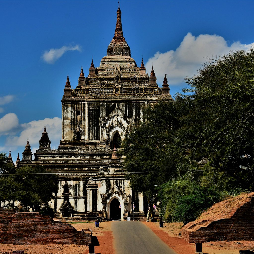Majestic Thatbyinnyu Temple in Bagan, Myanmar, surrounded by greenery and blue sky.