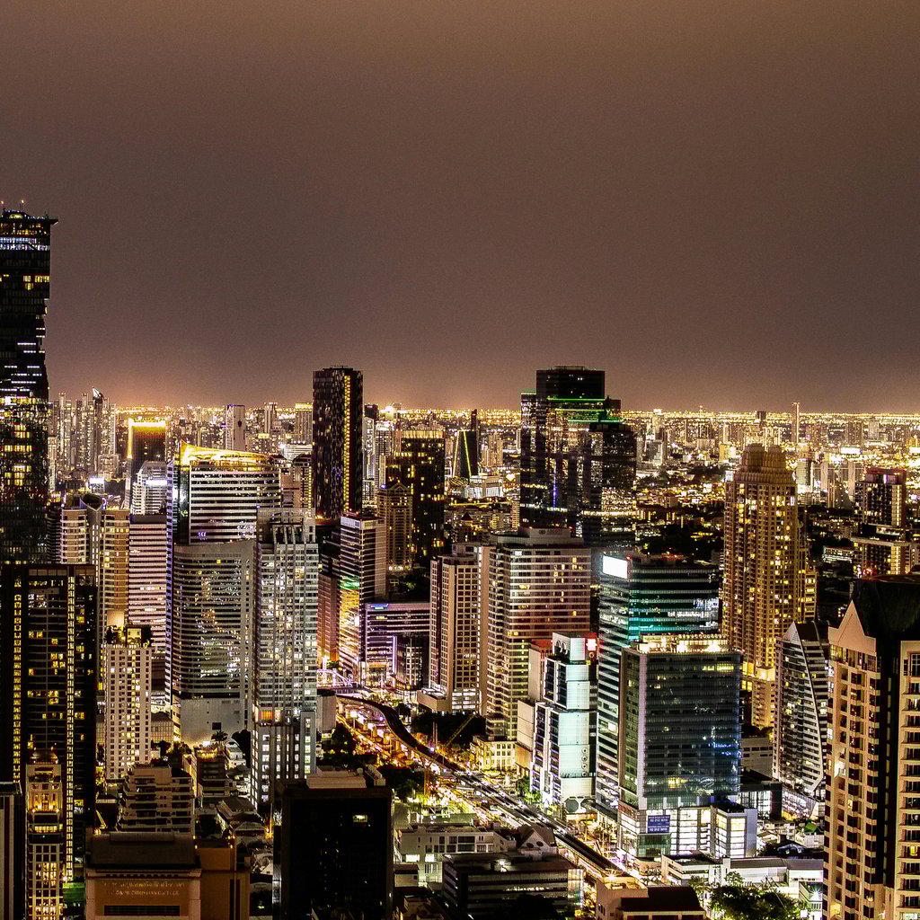 A vibrant night view of Bangkok's illuminated skyline featuring modern skyscrapers.