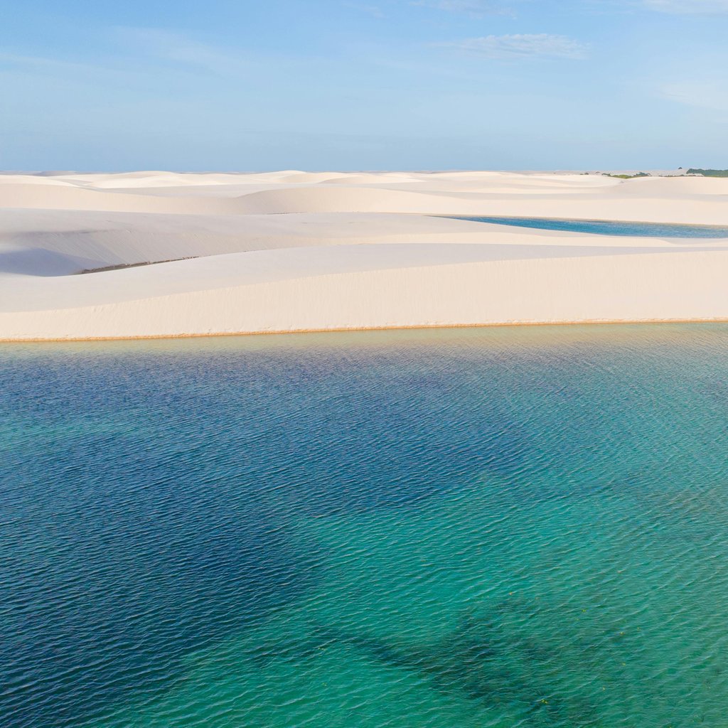 Discover the breathtaking sand dunes and turquoise lagoon of Lençóis Maranhenses National Park in Brazil.