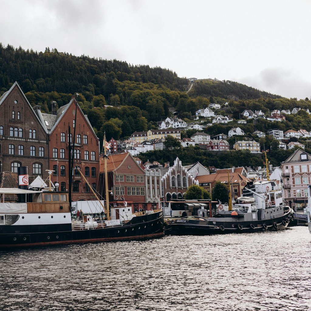 Scenic view of Bryggen's historic wharf with boats in Bergen, Norway on a cloudy day.