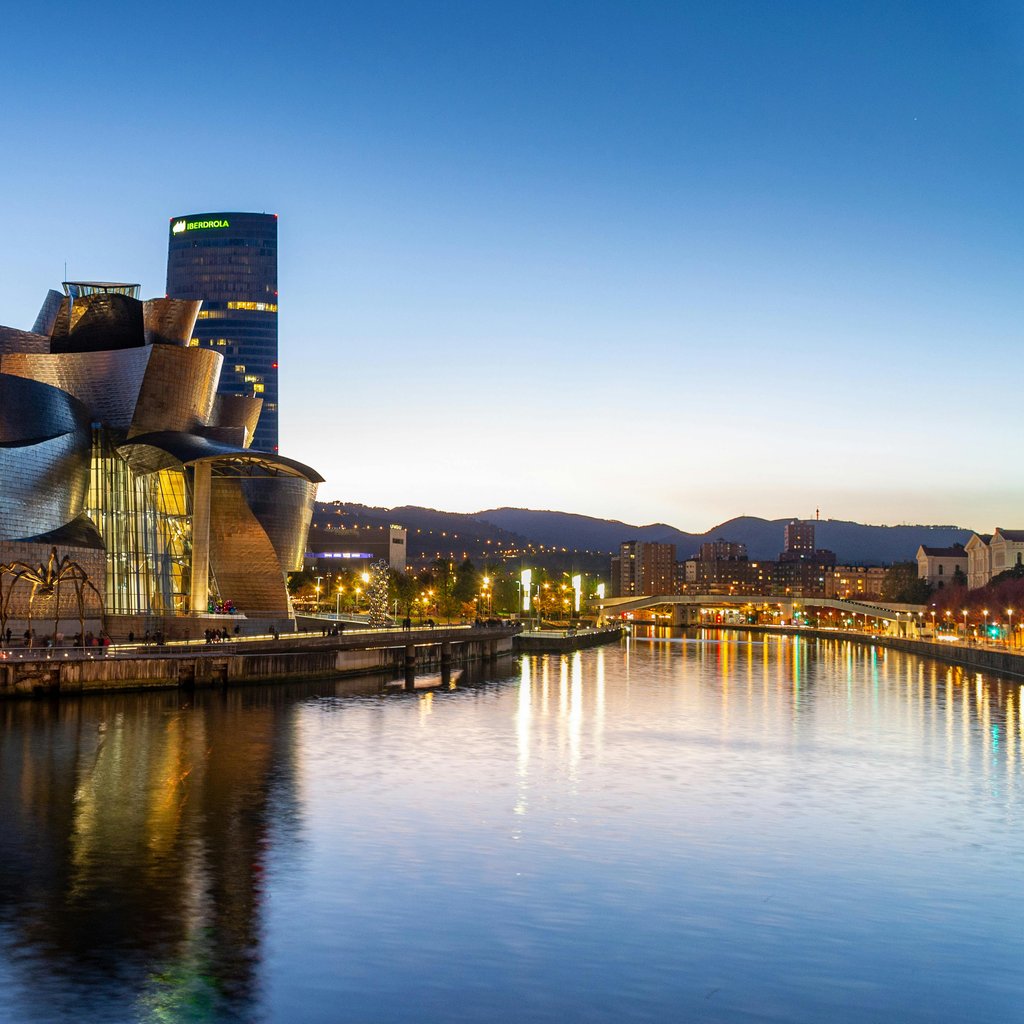 Stunning view of the Guggenheim Museum Bilbao reflecting in the Nervion River at dusk.