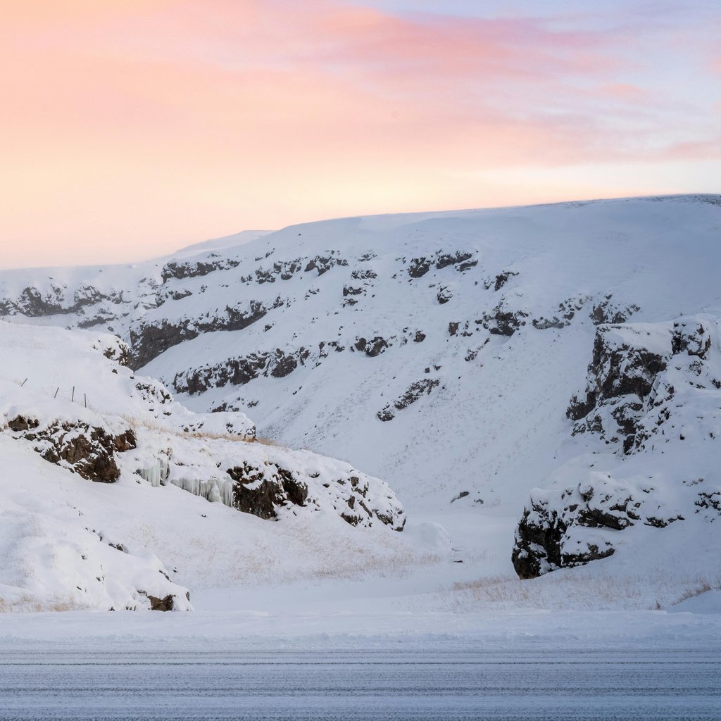 Captivating winter scene in Blönduós, Iceland; snowy hills under a pink sky.