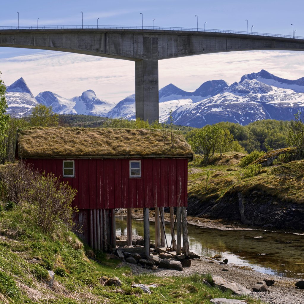 Saltstraumen Bridge and snowy mountain backdrop with cabin in scenic Norway landscape.