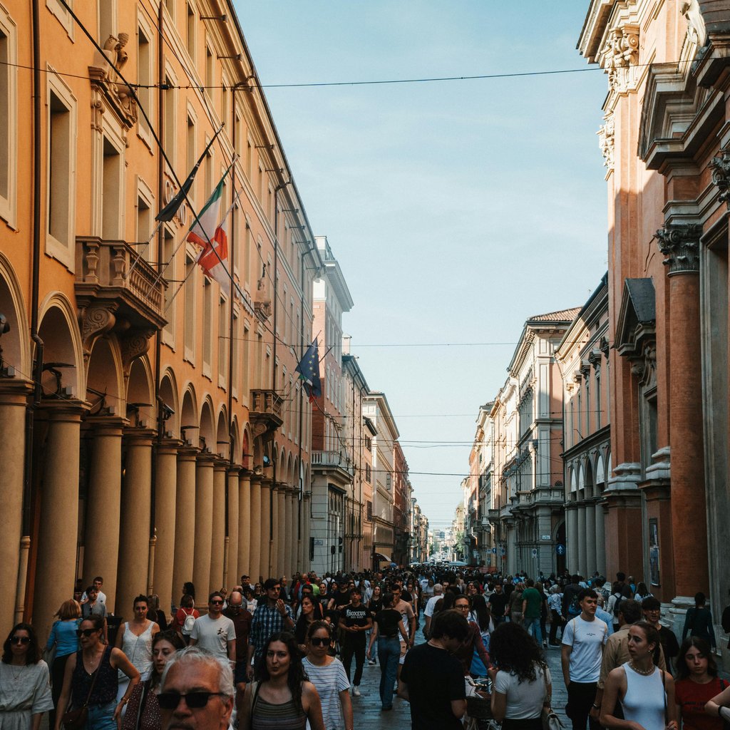 A vibrant urban scene in Bologna, Italy, showcasing historic architecture and a lively crowd.