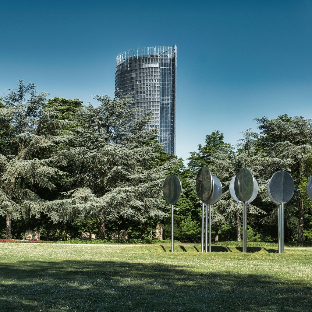 View of the Post Tower and modern art in a lush Bonn park.