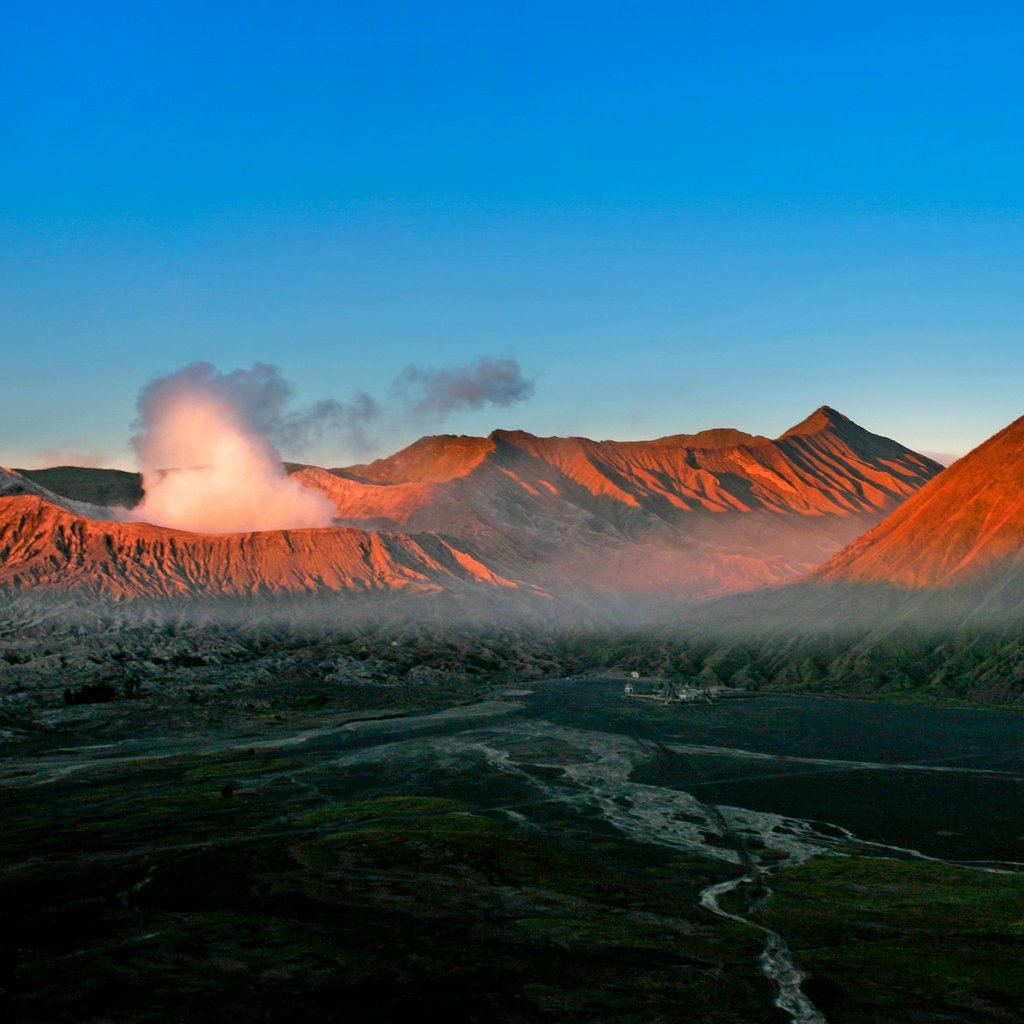 A breathtaking aerial view of Mount Bromo during sunrise with a vibrant sky and volcanic mist.