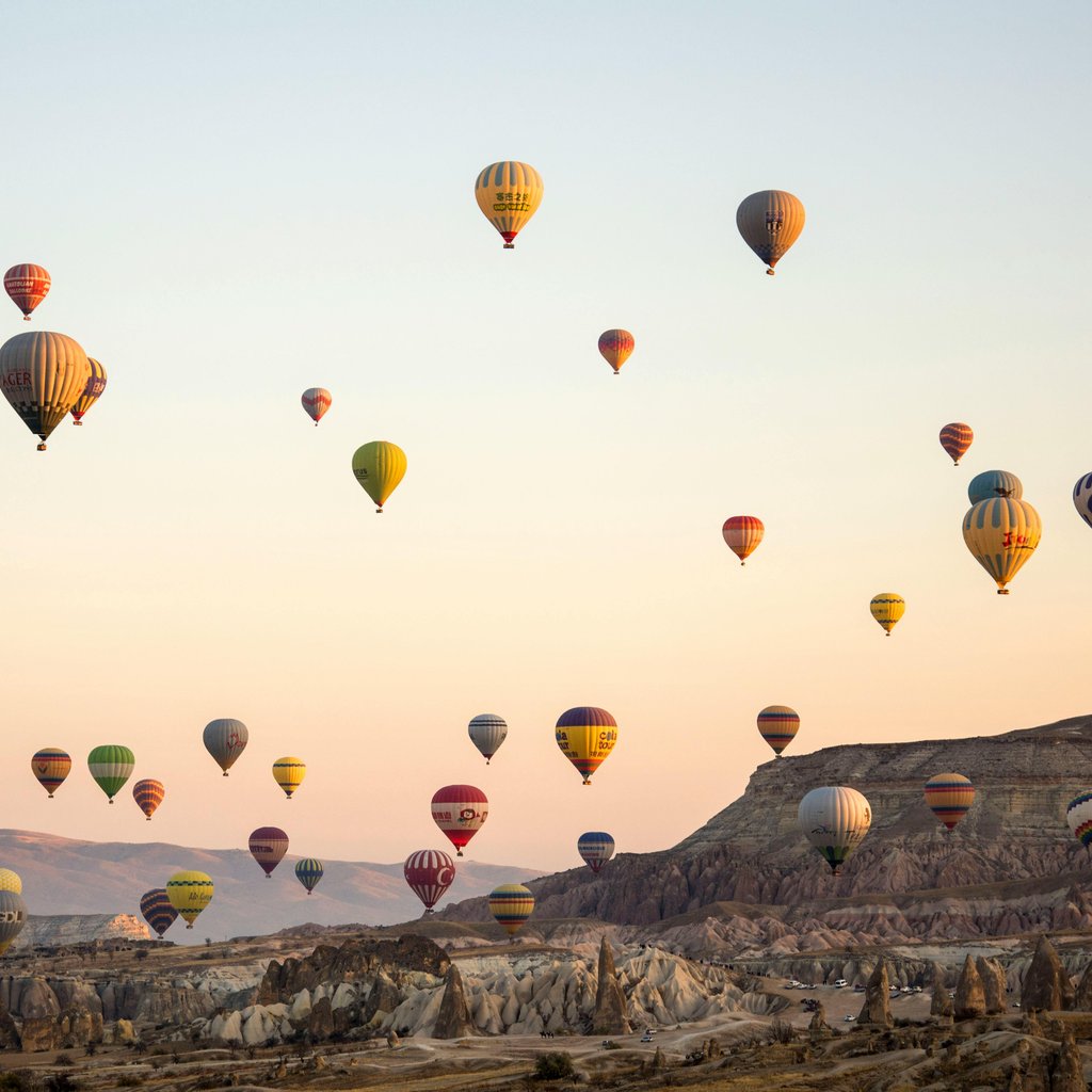 A breathtaking view of colorful hot air balloons soaring above Cappadocia's unique landscape during sunset.