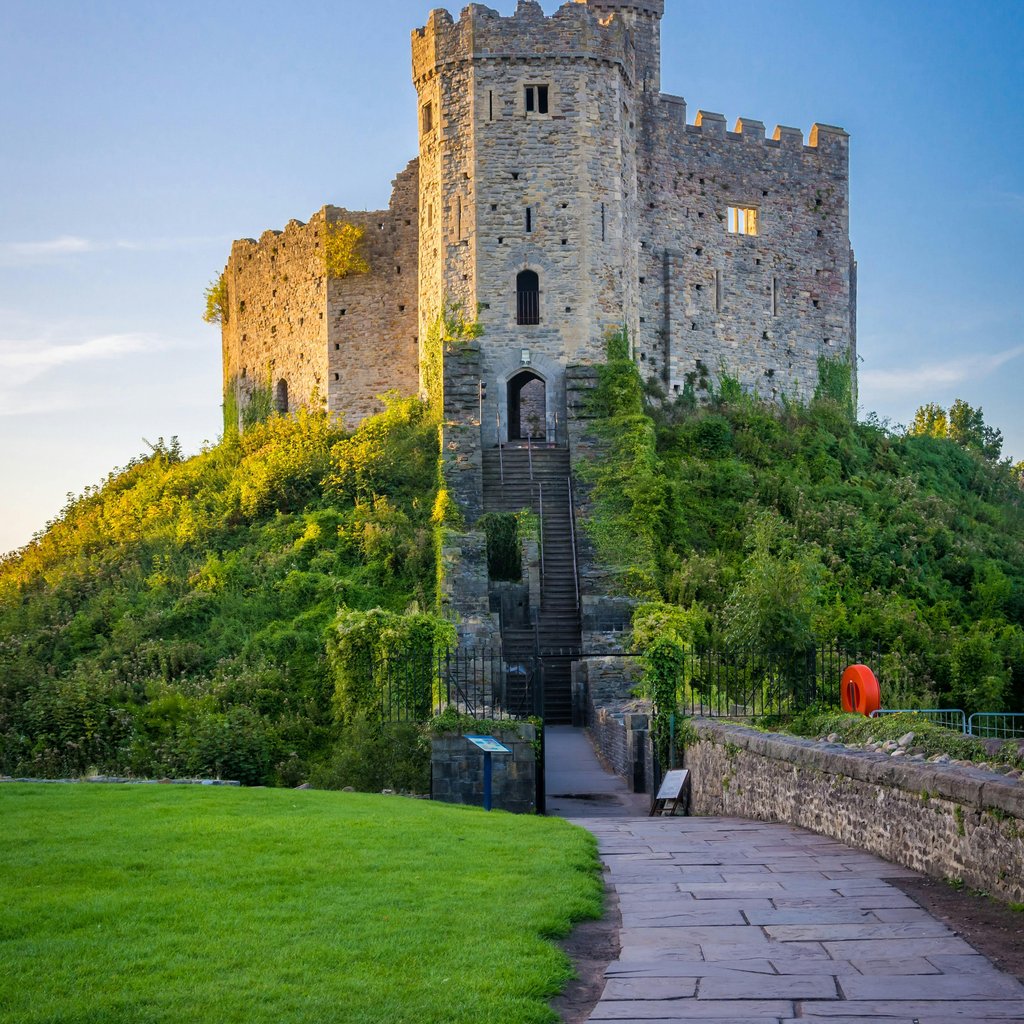 View of the historic Cardiff Castle in Wales with medieval architecture under a blue sky.