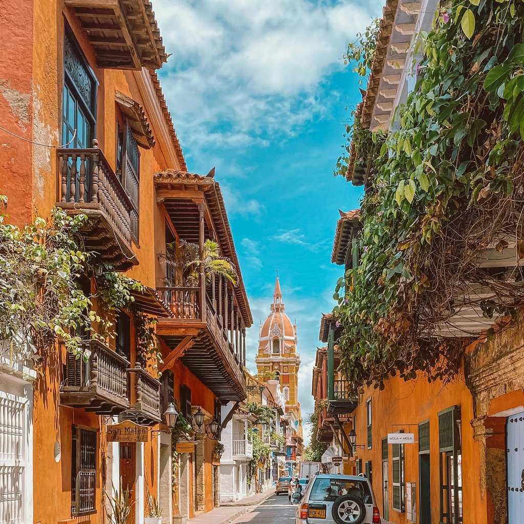 Charming street in Cartagena with vibrant buildings and cathedral in view, ideal for travel inspiration.