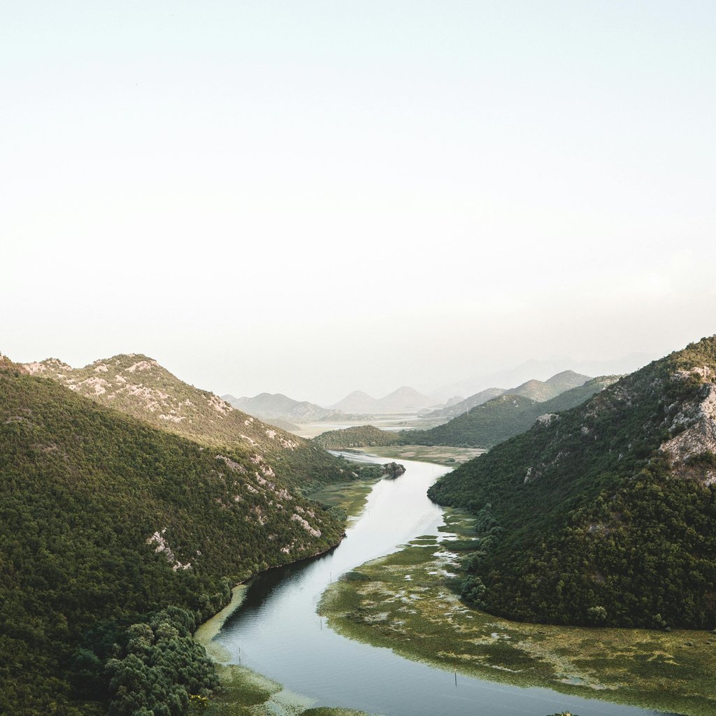 A scenic view of a winding river through lush mountains in Šinđon, Montenegro, ideal for nature lovers.