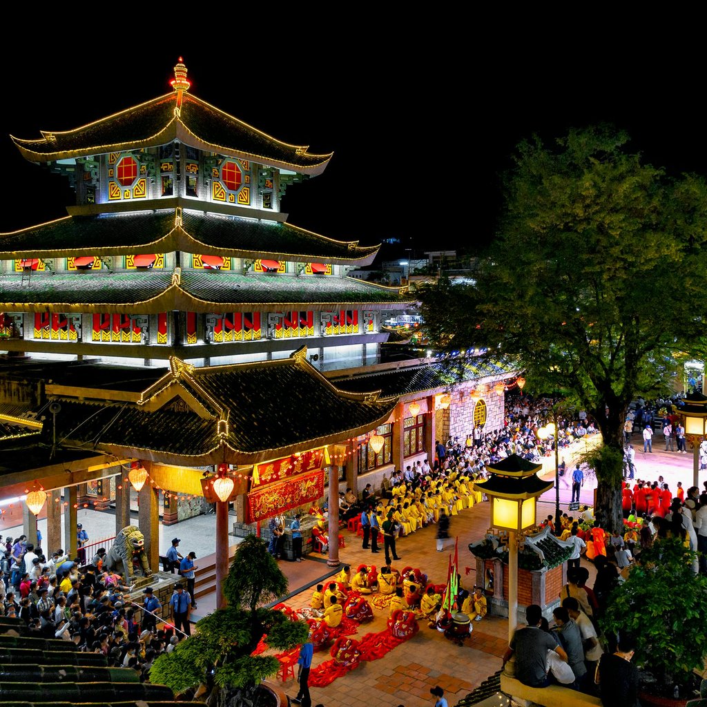 Brightly lit pagoda during a traditional festival in An Giang, Vietnam, showcasing cultural and architectural beauty.
