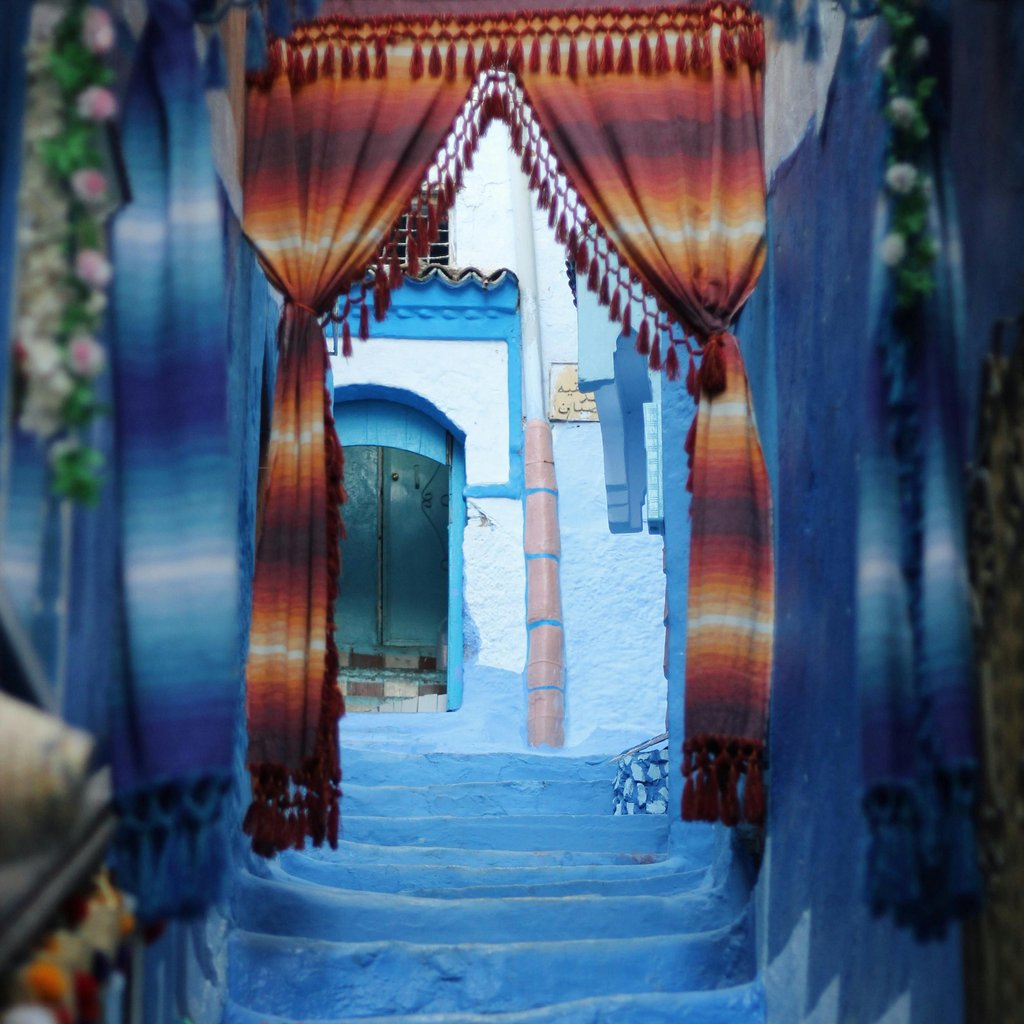 Vivid blue stairs adorned with textiles and decor in the picturesque streets of Chefchaouen, Morocco.