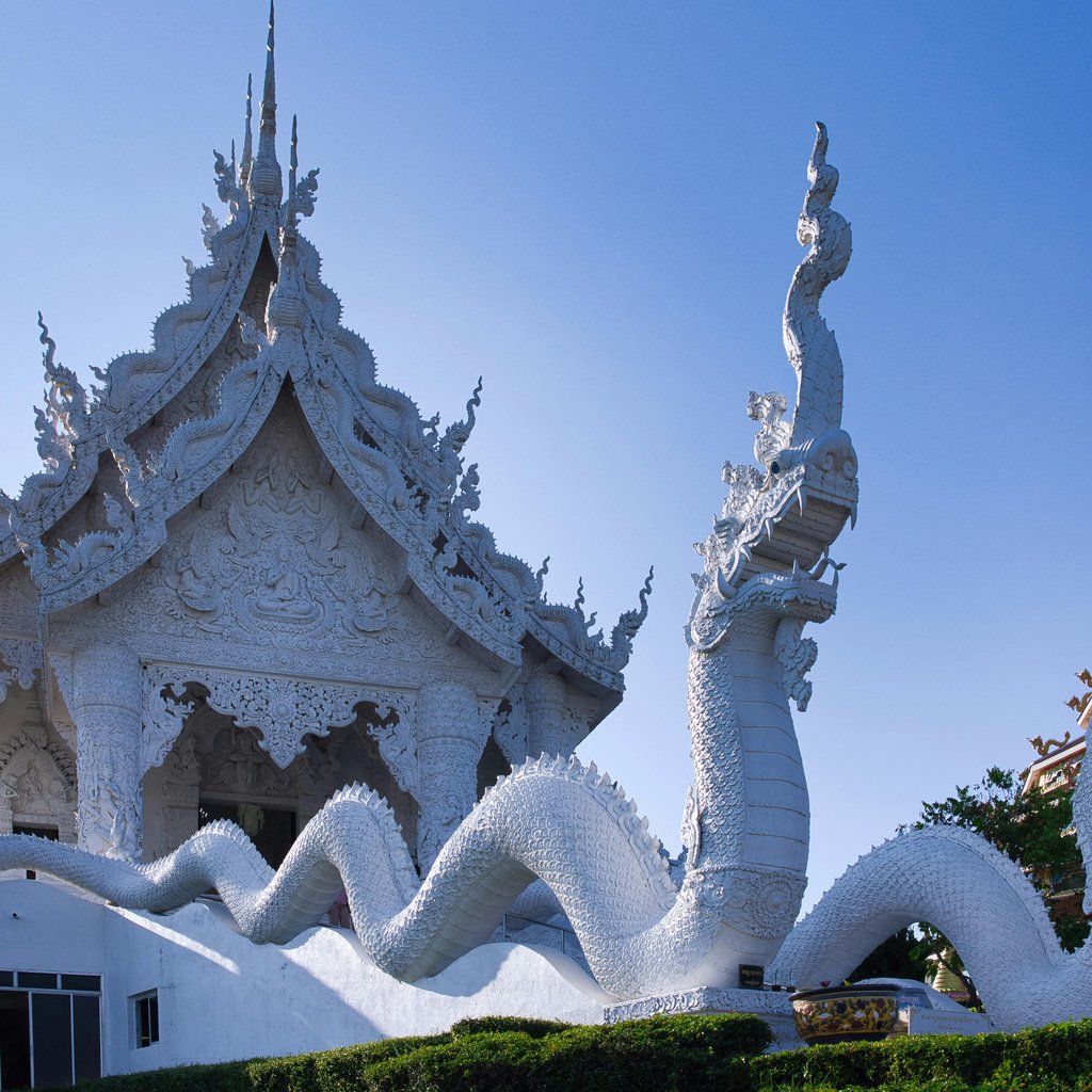 Stunning ornate white temple with dragon sculptures in Chiang Rai, Thailand.
