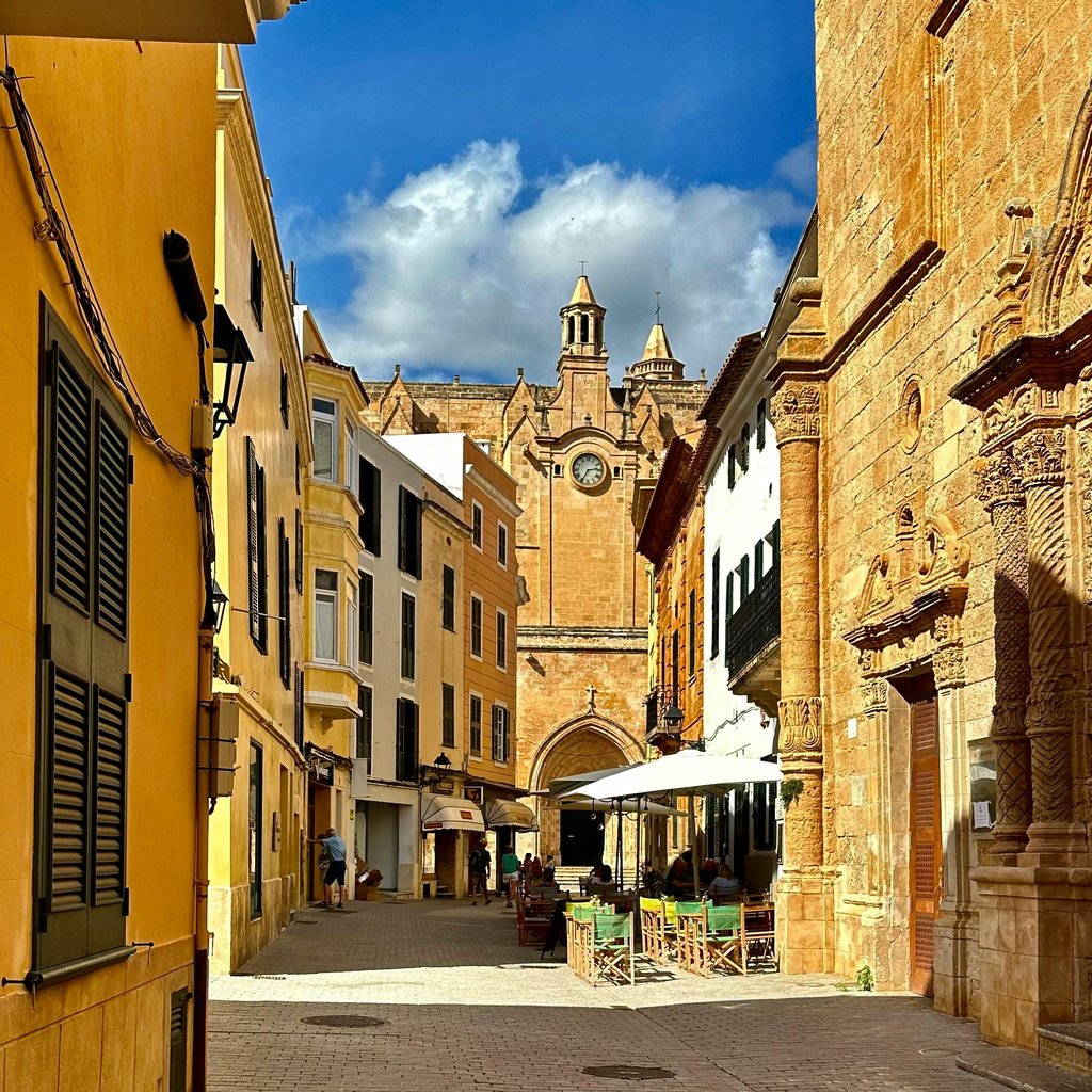 A picturesque street scene in Ciutadella, Menorca with historic architecture and a vibrant atmosphere.