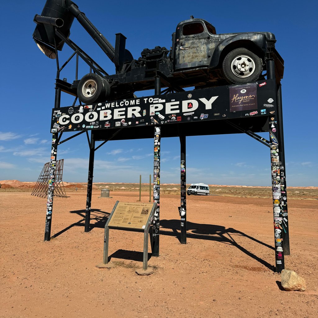 A vintage truck displayed atop a sign welcomes visitors to Coober Pedy, an iconic Australian opal mining town.