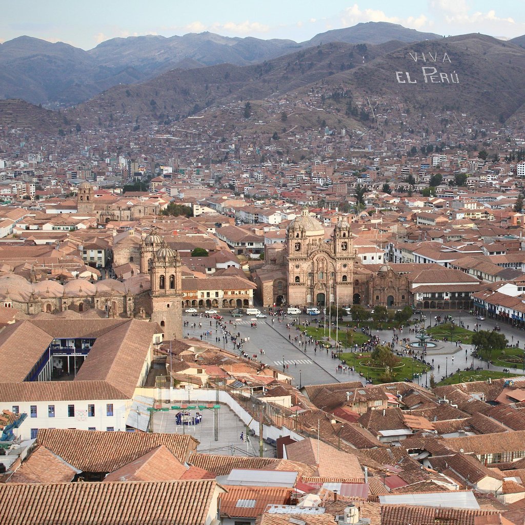 Aerial view of historic Plaza de Armas in Cusco, Peru with scenic mountains.