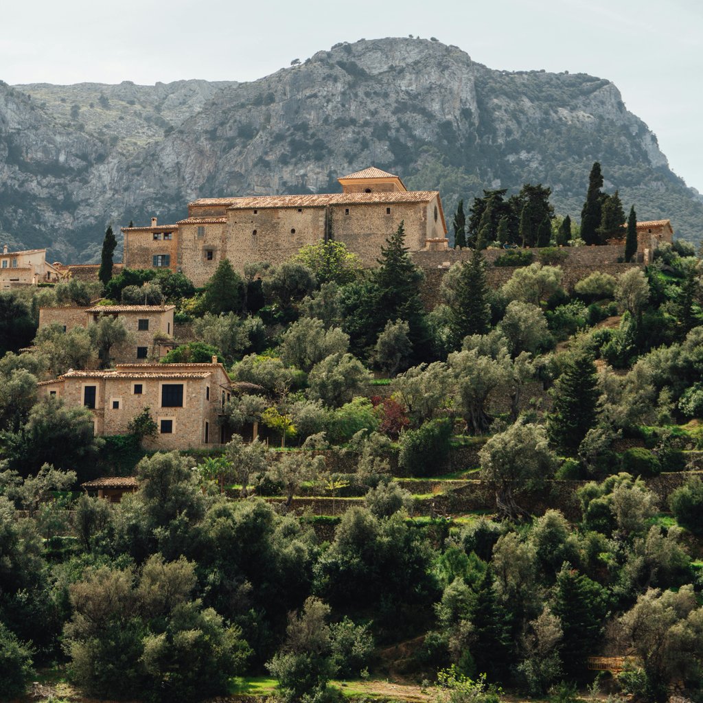 A picturesque view of Deià village with traditional stone buildings and lush greenery in Mallorca, Spain.