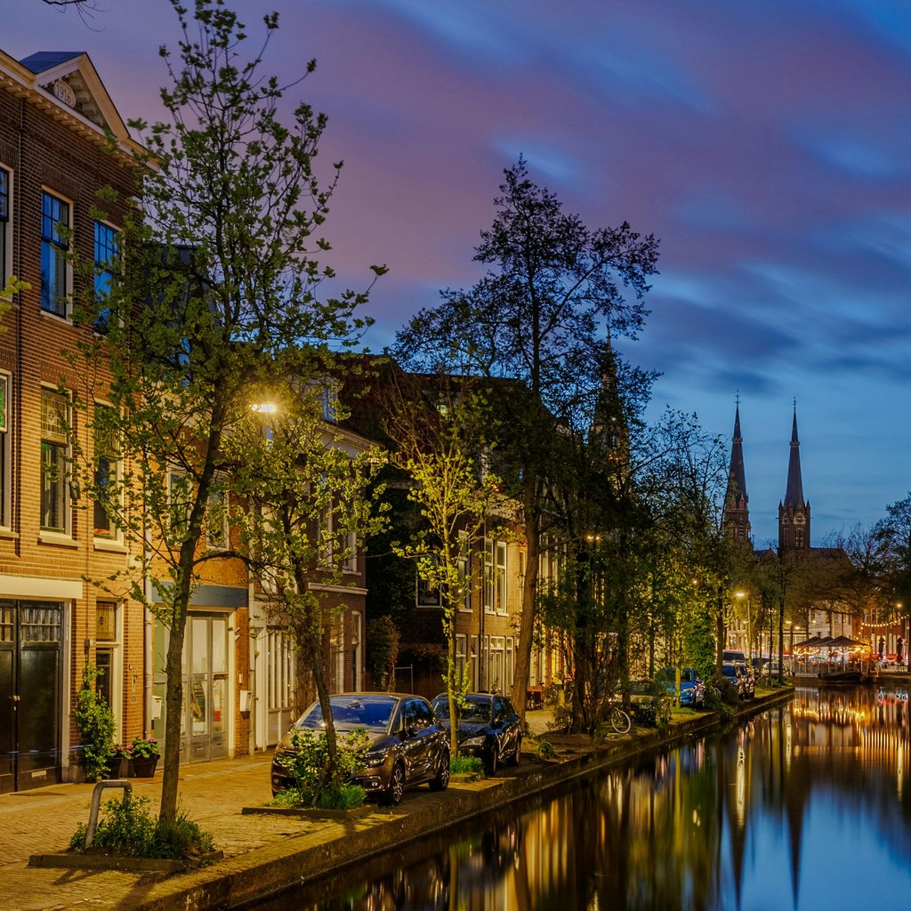 Scenic view of a canal in Delft, Netherlands at twilight with charming architecture and vibrant evening skies.
