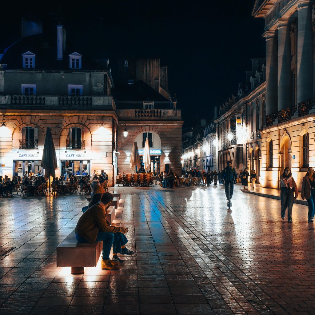Explore the vibrant nightlife of Dijon, France with illuminated architecture and lively streets.