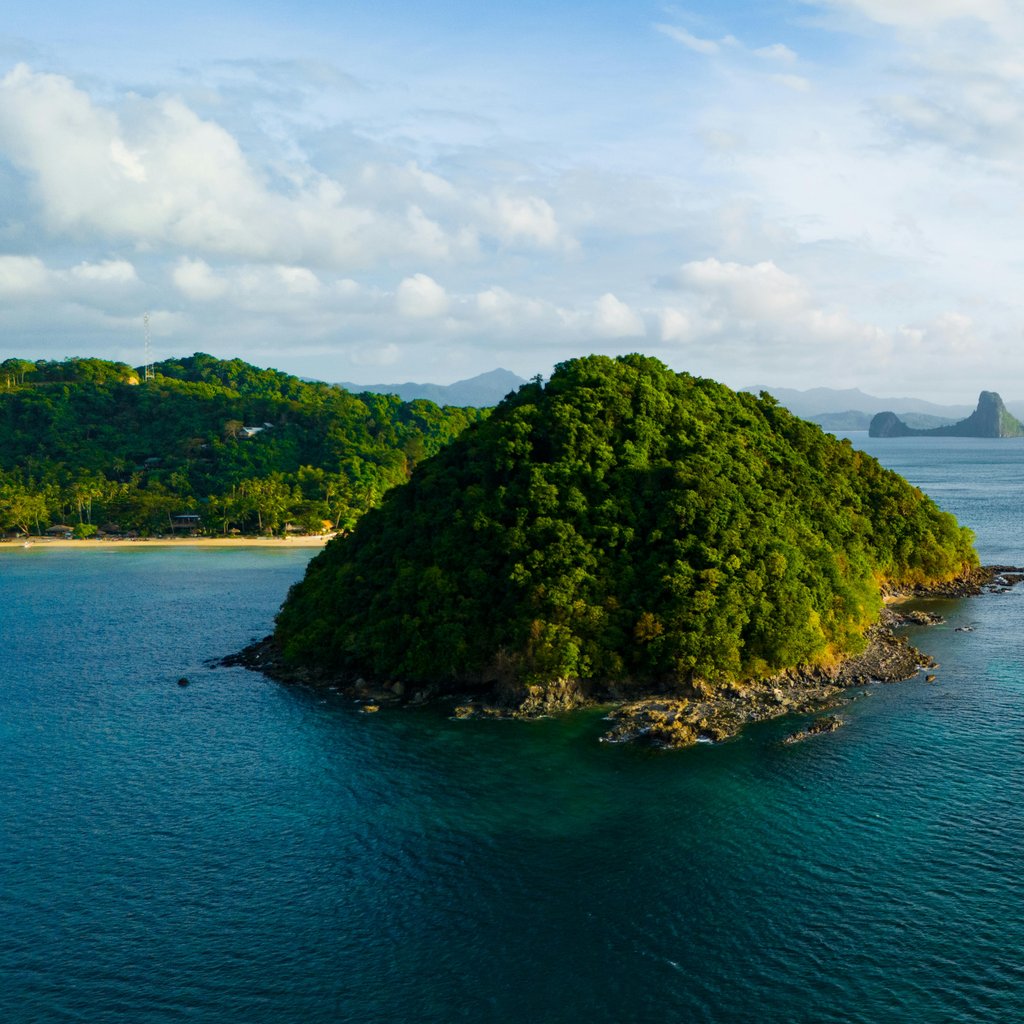 A breathtaking aerial view of the lush green islands of El Nido, Philippines, surrounded by crystal blue waters.