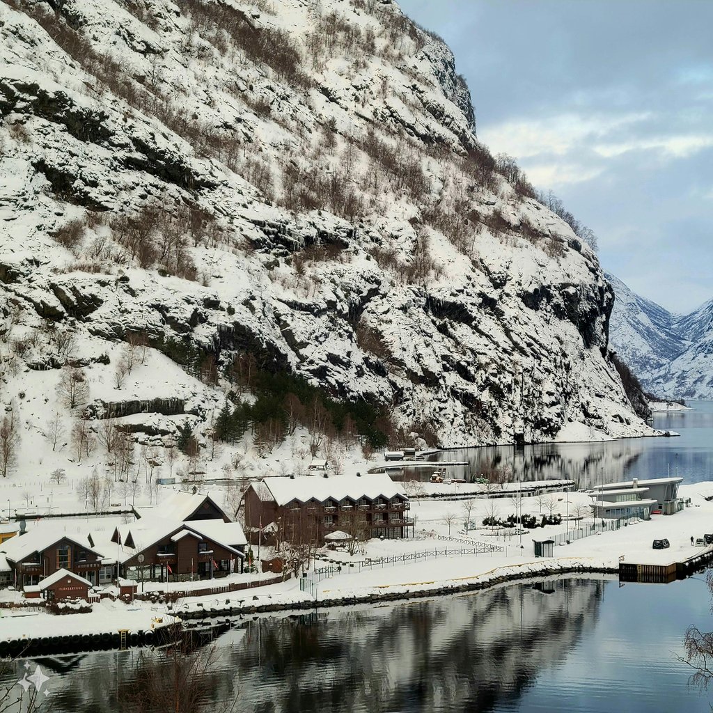 Snow-covered port in Flåm, Vestland, Norway reflecting mountains in winter.