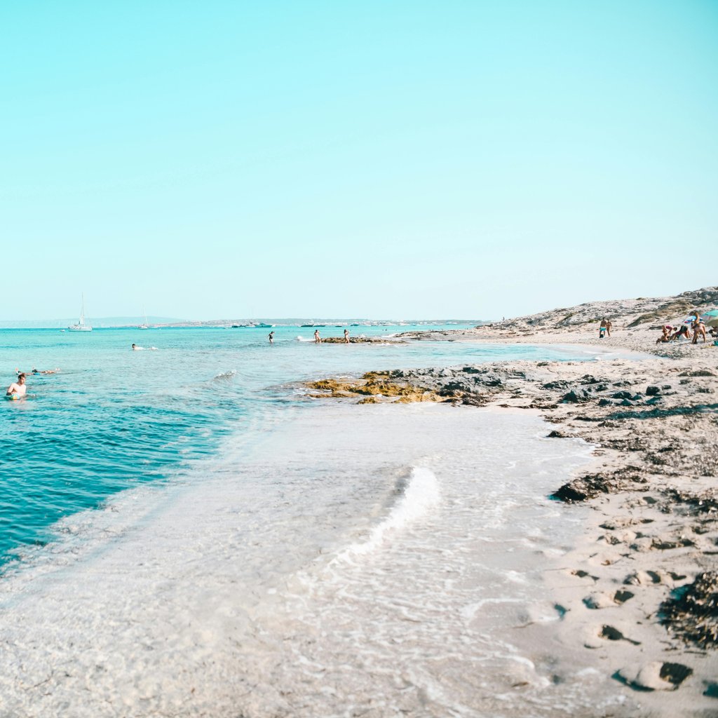 Relaxing beach scene in Formentera, Spain with clear blue waters and a serene horizon.