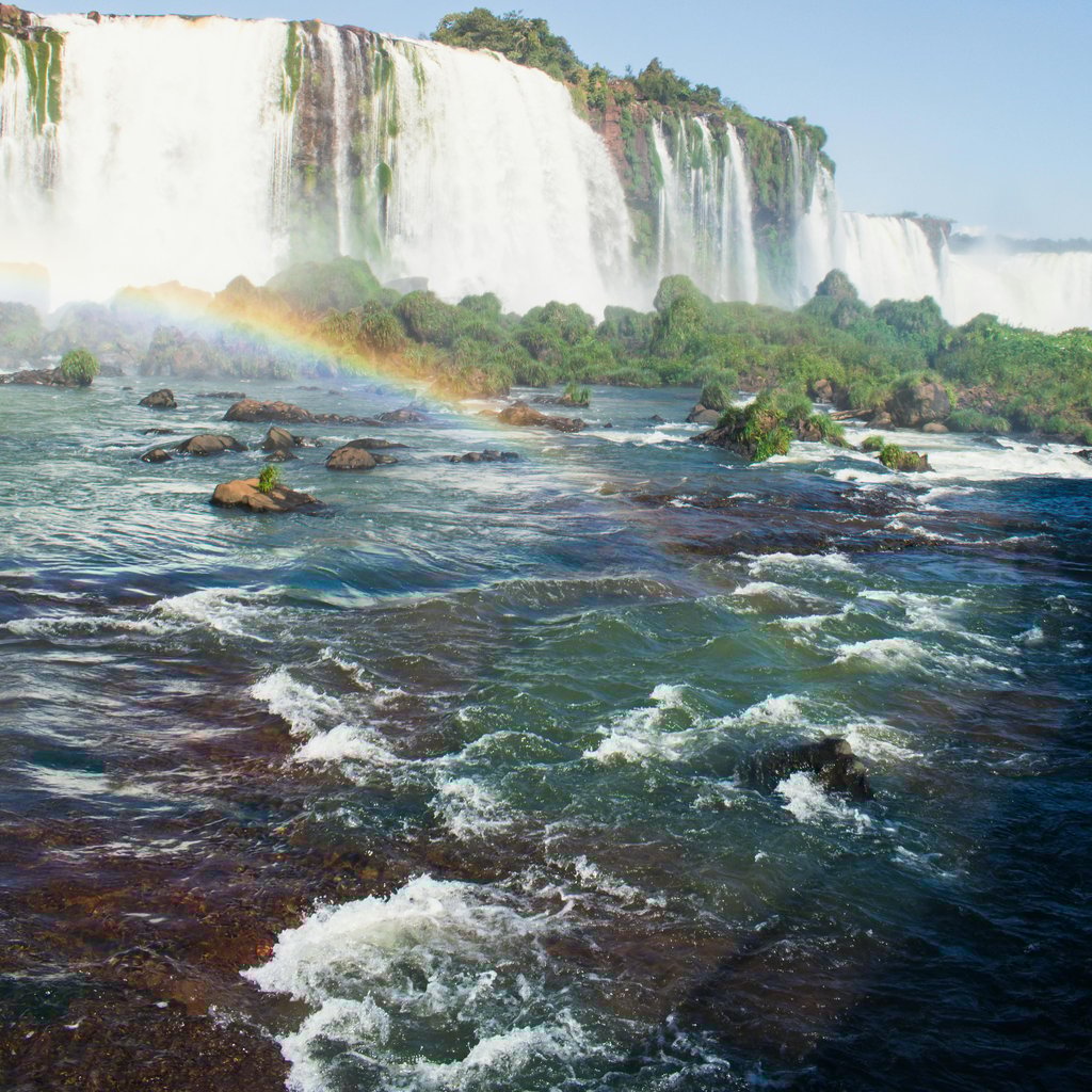 Breathtaking view of Iguazu Falls in Foz do Iguaçu, Brasil, with a vivid rainbow and lush greenery.
