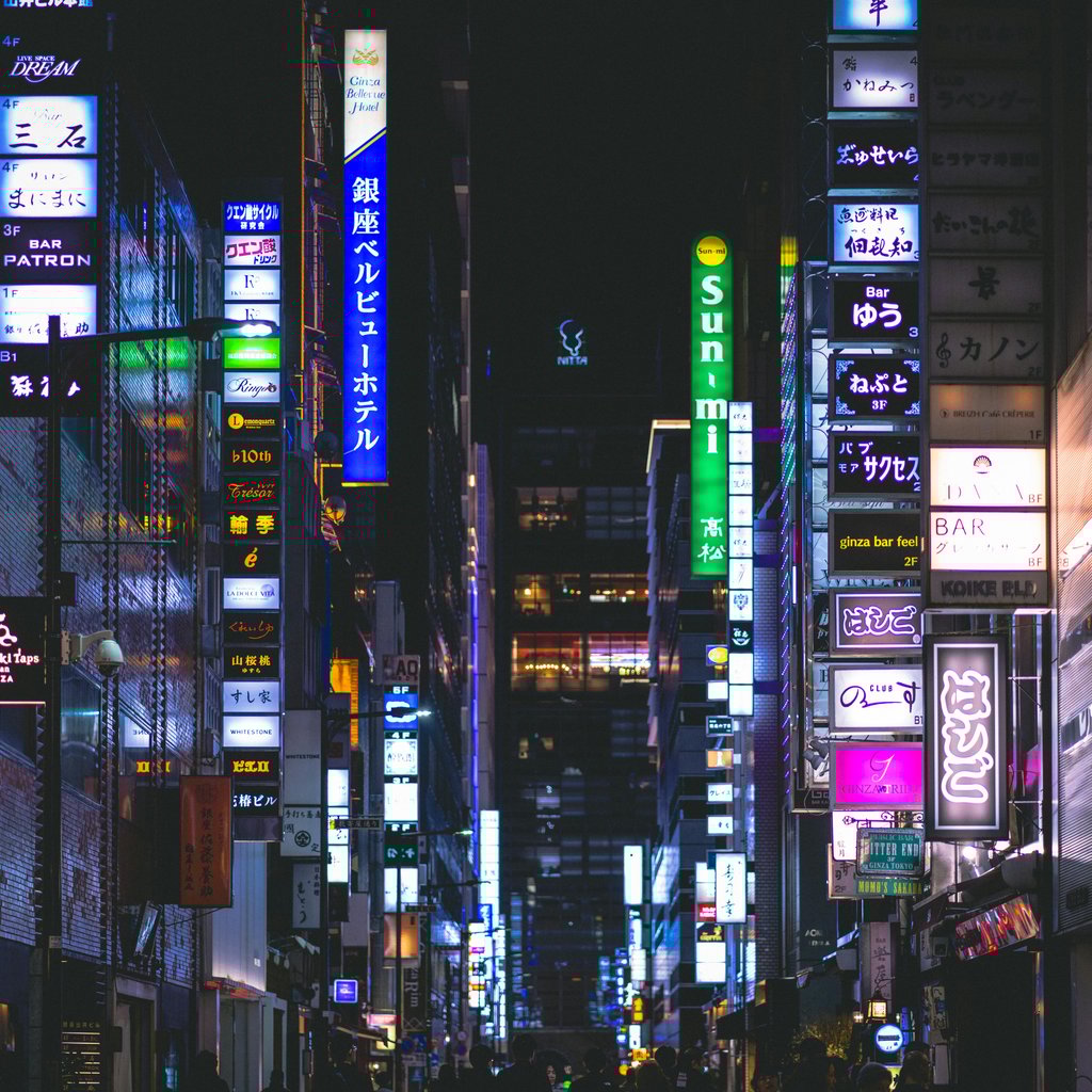 Colorful neon signs illuminate the bustling streets of Ginza, Tokyo at night, capturing urban nightlife.
