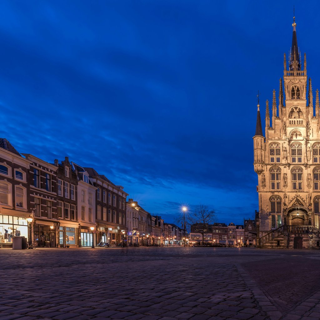 Stadhuis van Gouda illuminated against a deep blue evening sky in Gouda, Netherlands.
