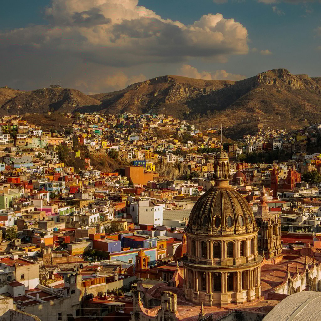 A vibrant aerial view of Guanajuato City showcasing colorful architecture and mountainous backdrop.