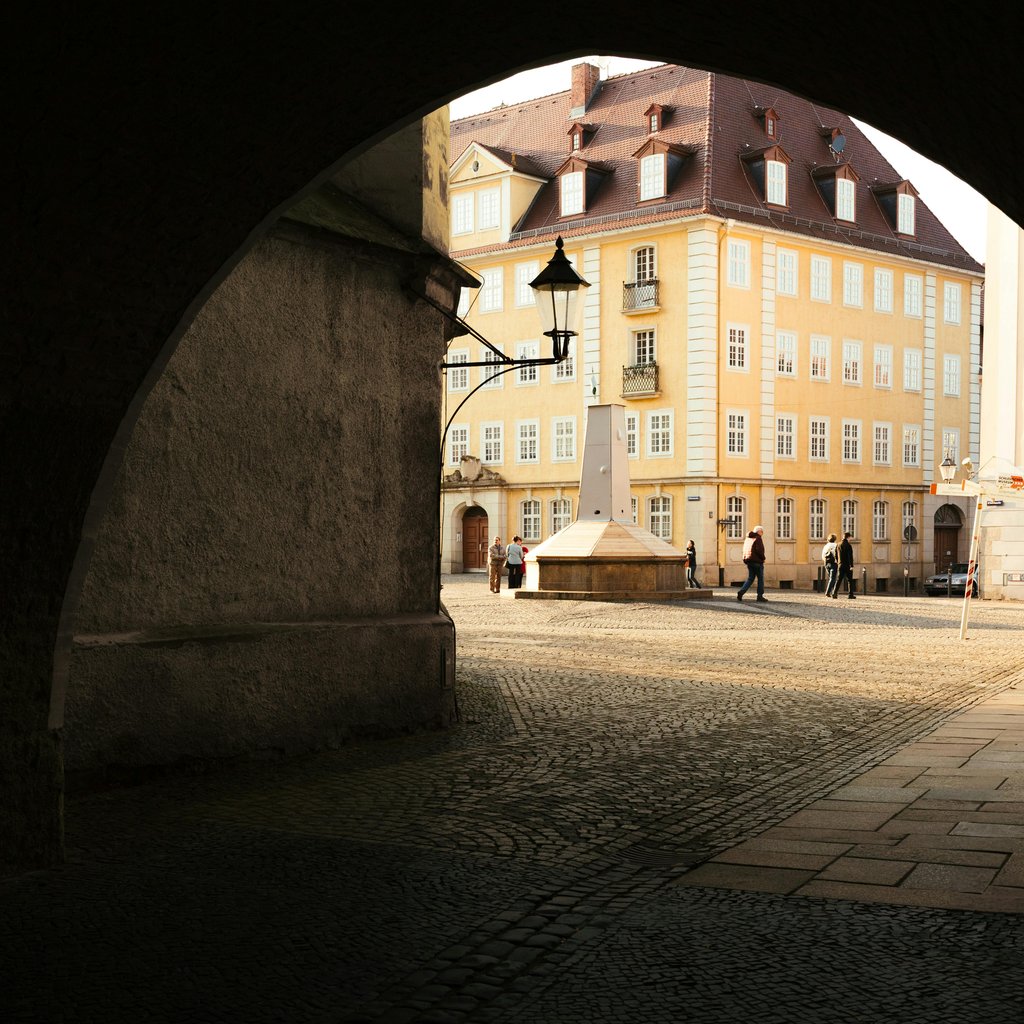A scenic street view in Görlitz, Saxony, Germany, featuring classic architecture under an archway.