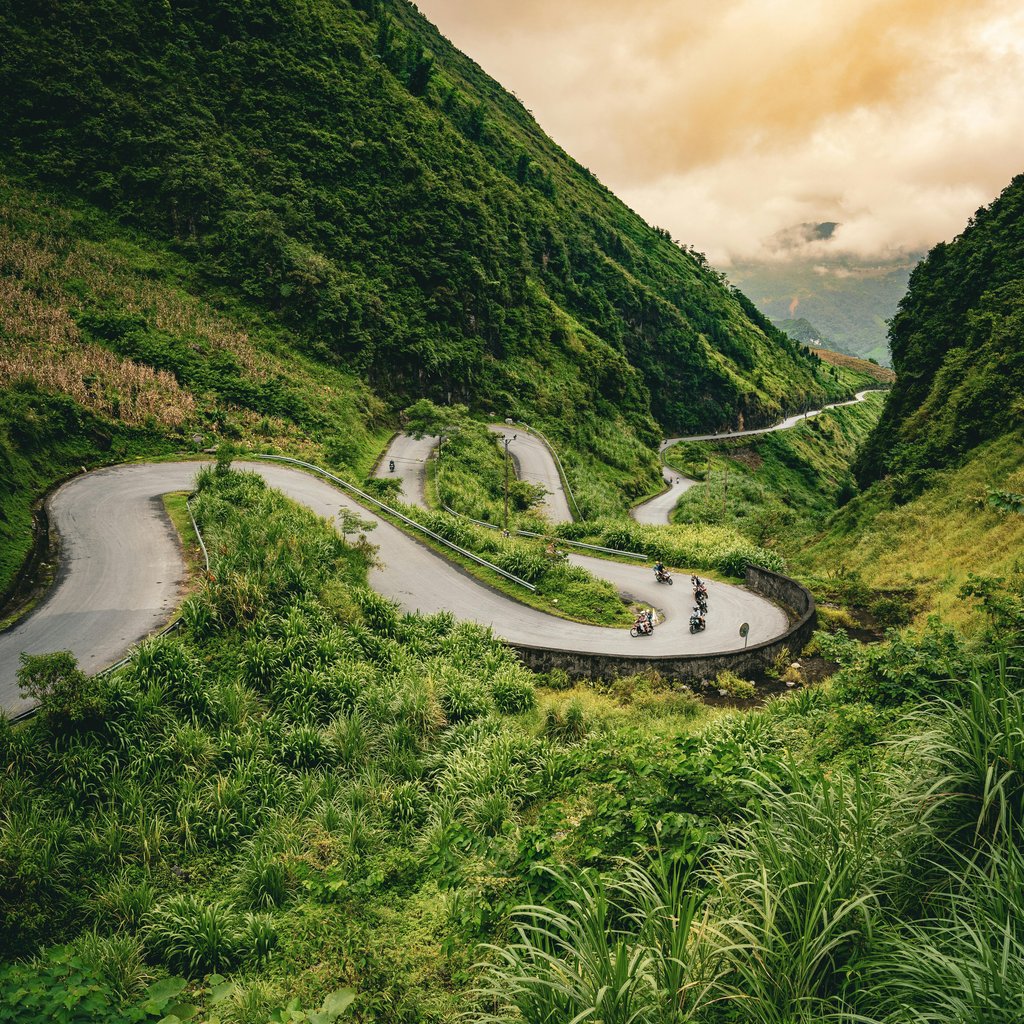 Serene winding road through lush Hà Giang mountains, perfect for adventure travel.