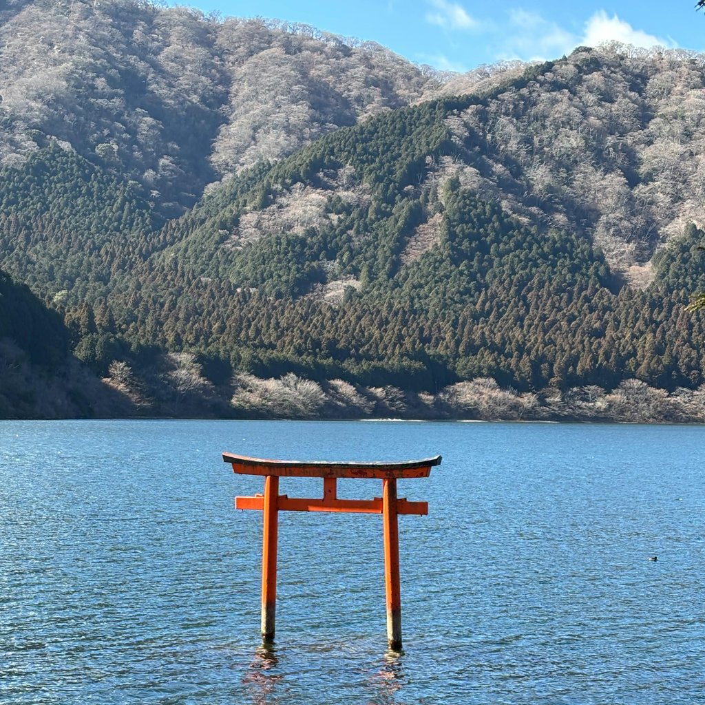 Idyllic view of a Torii gate on Lake Ashi in Hakone, Japan against a backdrop of lush mountains.