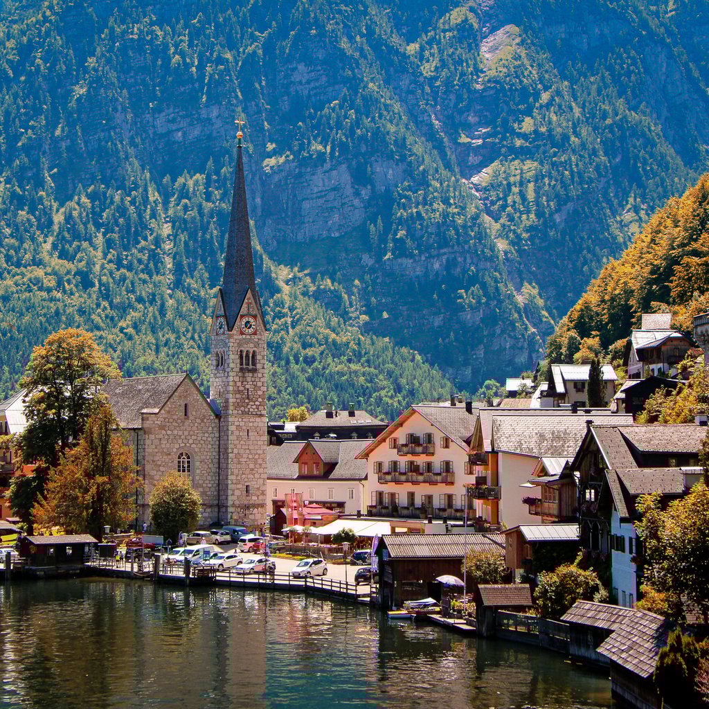 Picturesque view of Hallstatt, Austria with a prominent church by the waterfront, surrounded by mountains.