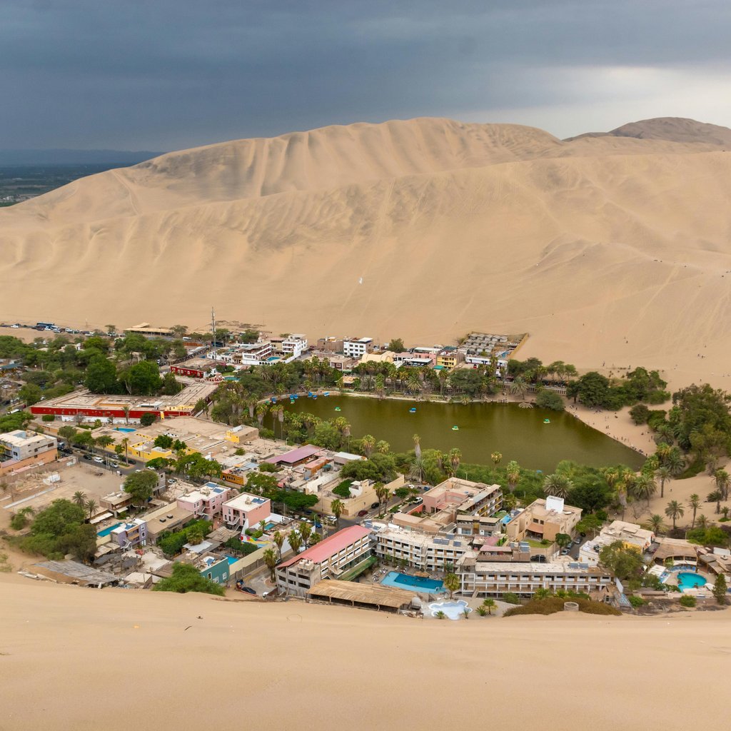 Stunning aerial view of Huacachina Oasis surrounded by sand dunes in Ica, Peru.