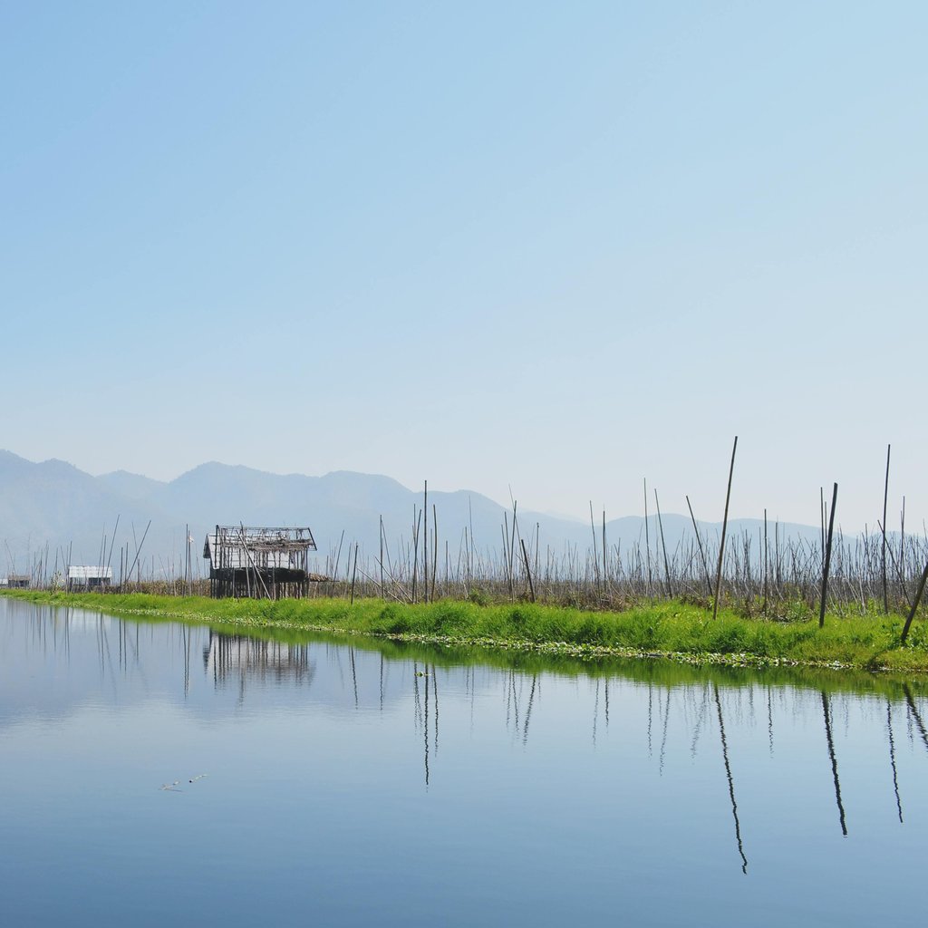 Serene view of floating villages and clear skies at Inle Lake in Myanmar.