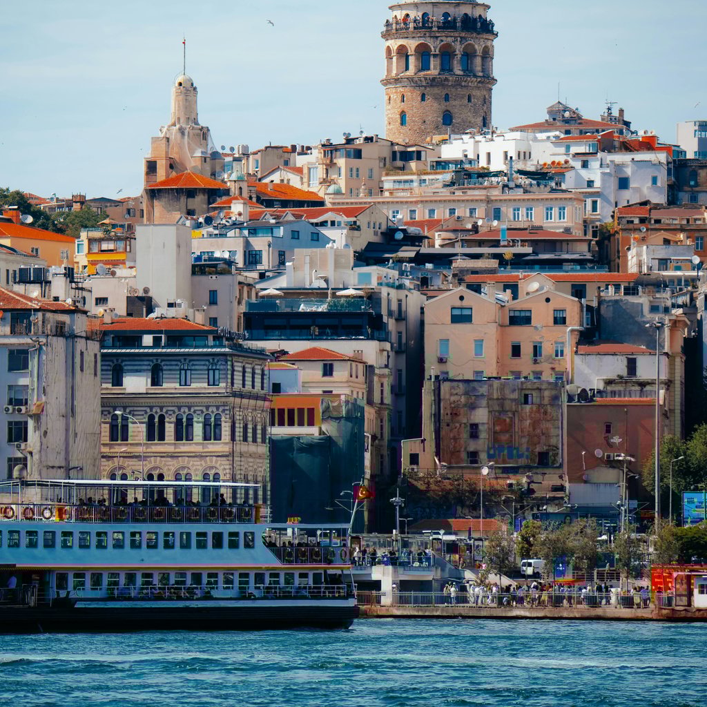 Scenic view of Galata Tower and vibrant architecture by the waterfront in Istanbul, Turkey.