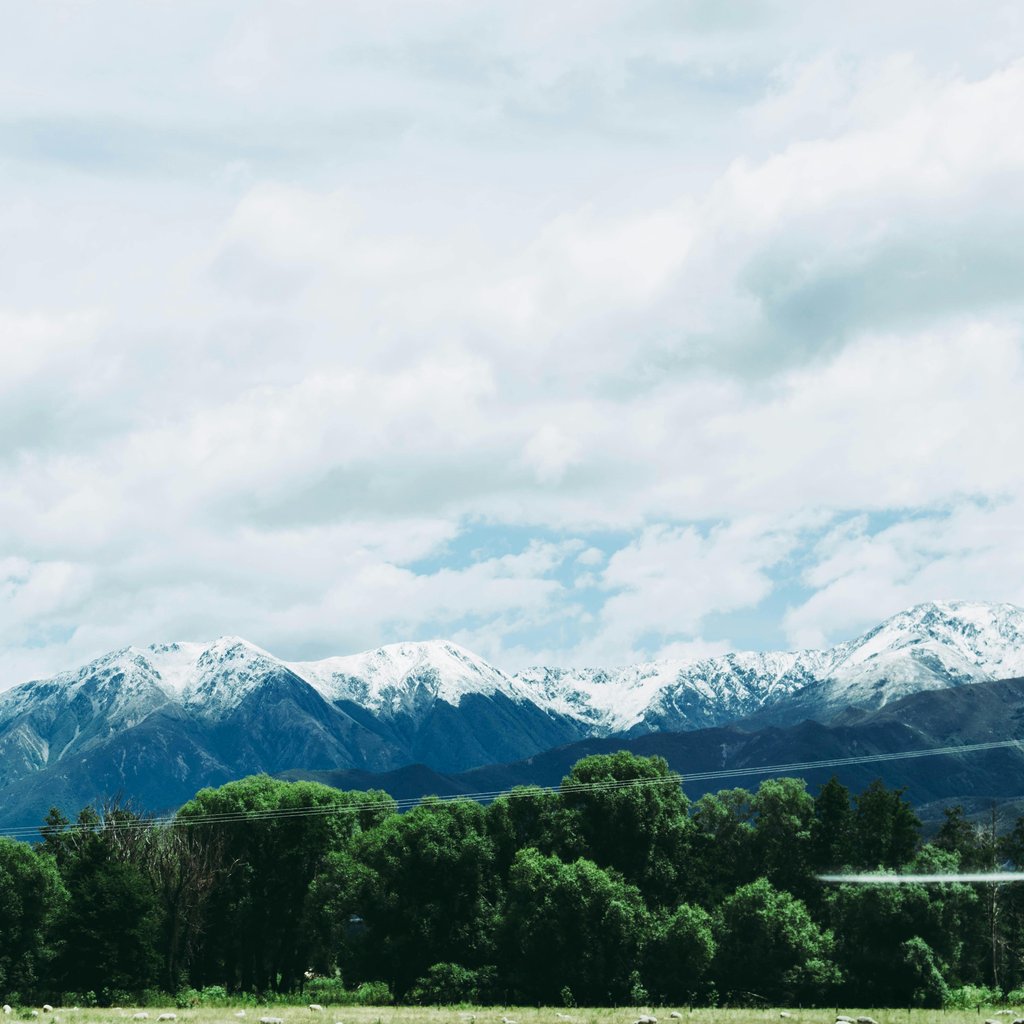 Majestic snow-capped mountains under a cloudy sky in Kaikoura, New Zealand, showcasing winter beauty and serene nature.