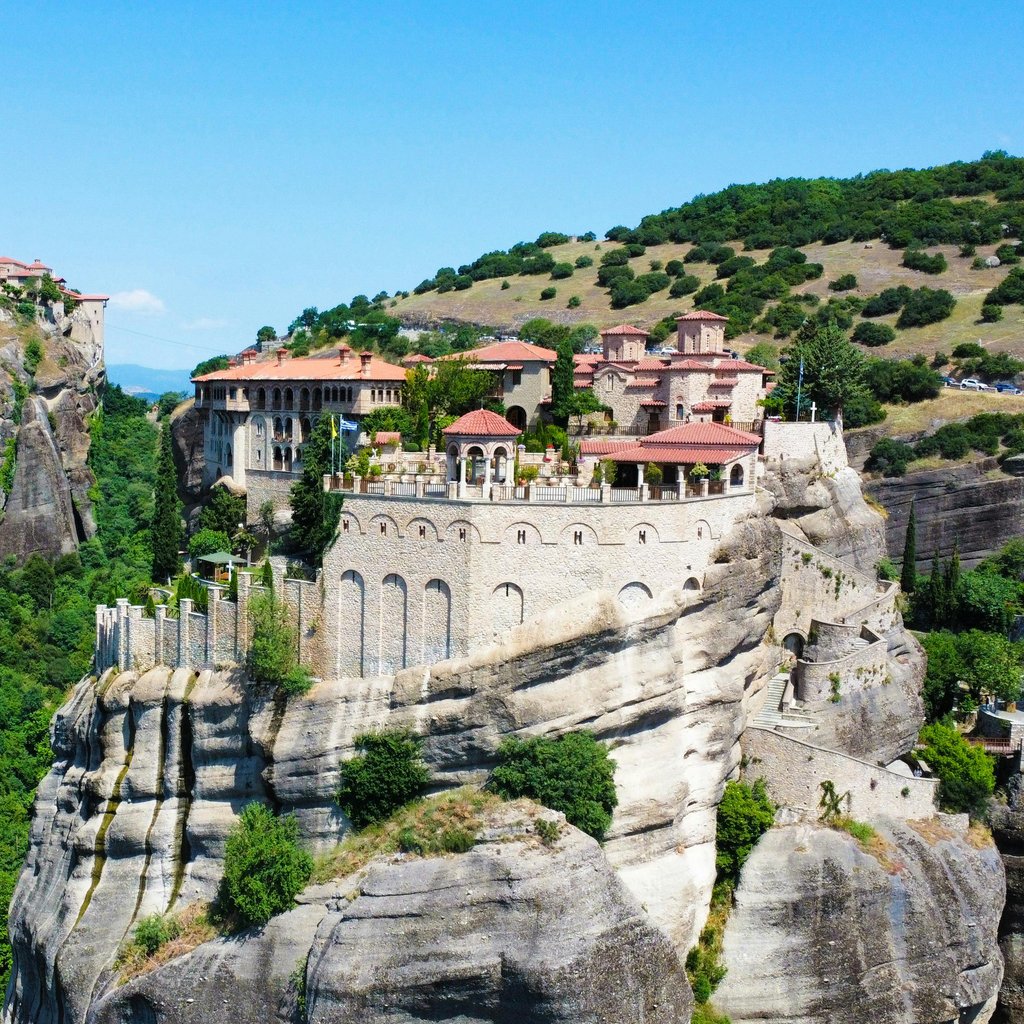 Stunning aerial landscape of the Meteora monasteries perched atop dramatic cliffs in Kalampaka, Greece.