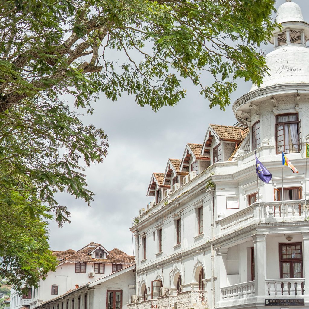 Lively street scene with colonial-era buildings and tuk-tuks in Kandy, Sri Lanka.