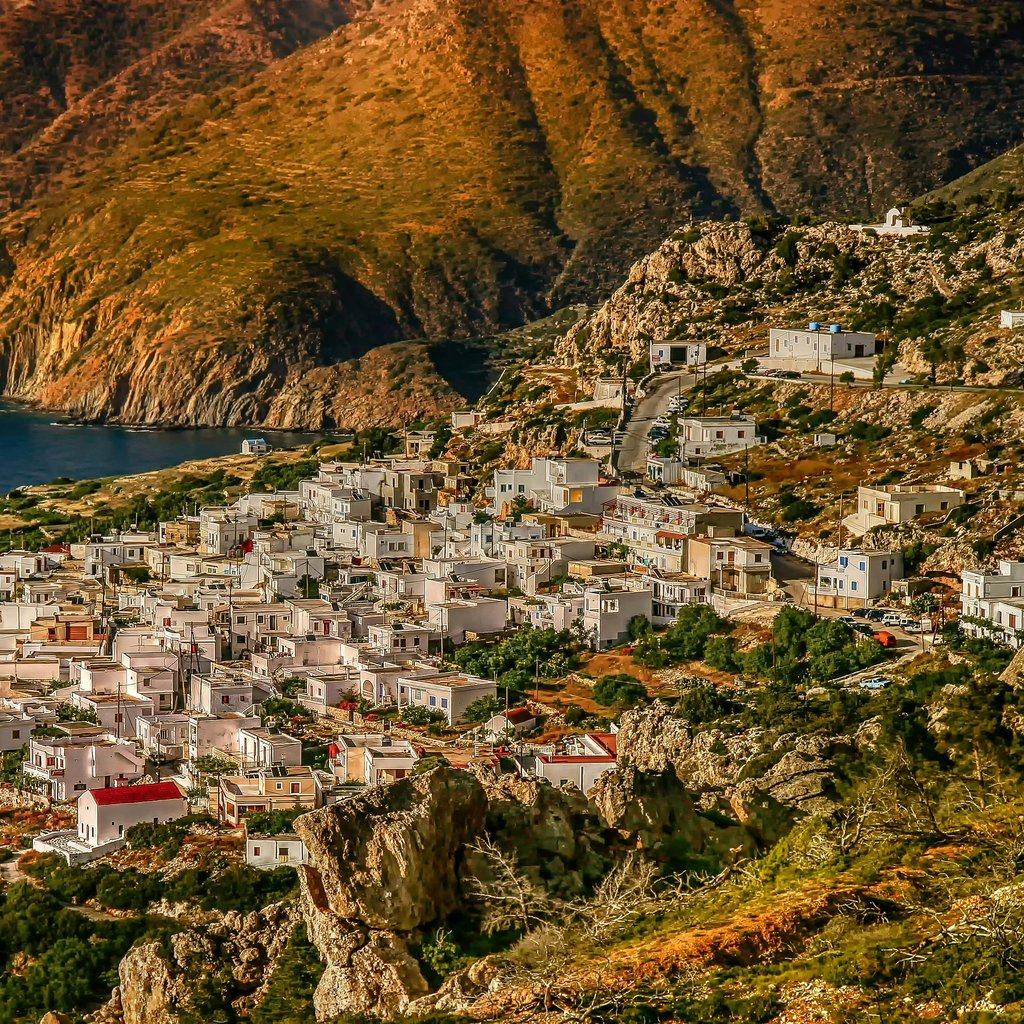 Aerial view of a picturesque village in Karpathos, Greece, surrounded by mountains and sea.