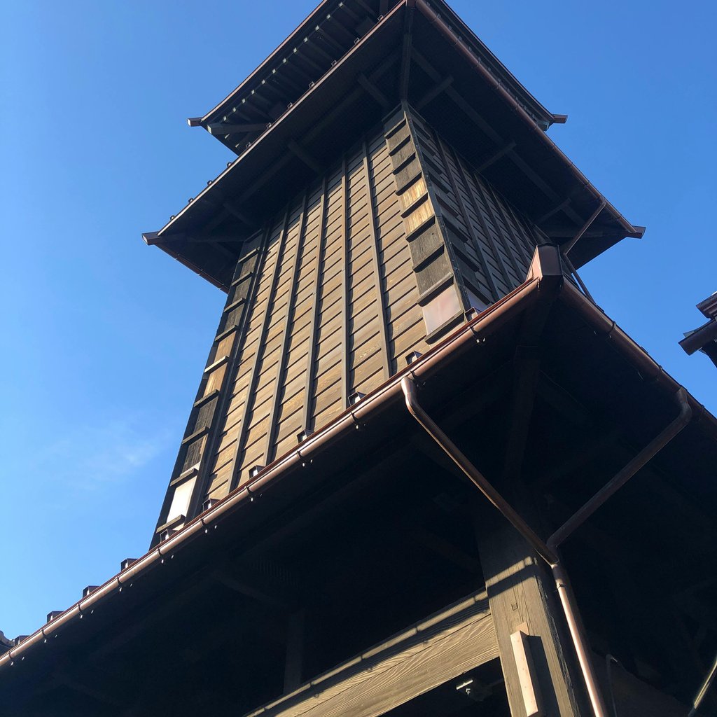 Low angle view of a historic bell tower in Kawagoe, Japan, against a clear blue sky.