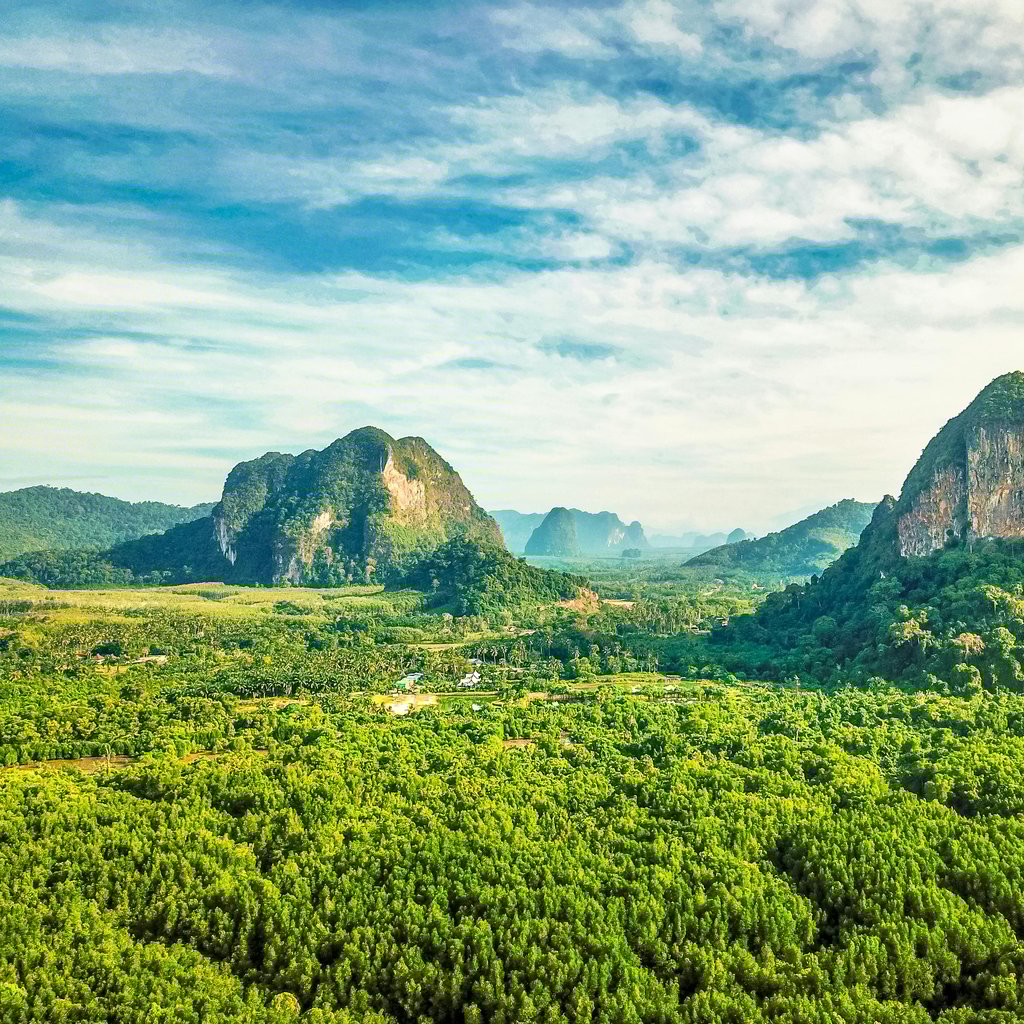 Explore the lush green landscape and majestic mountains of Thailand in this breathtaking aerial photograph.