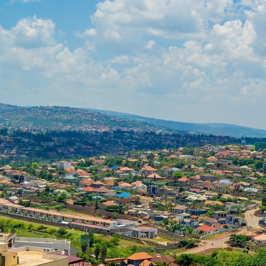 Aerial view of Kigali cityscape with colorful rooftops and vibrant greenery under a bright sky.