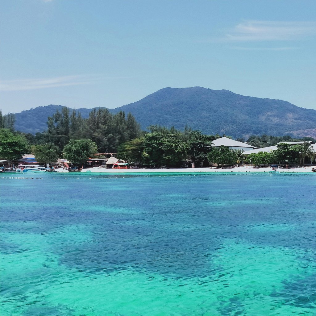 Crystal-clear waters and lush mountains in Satun, Thailand offer a stunning tropical retreat.