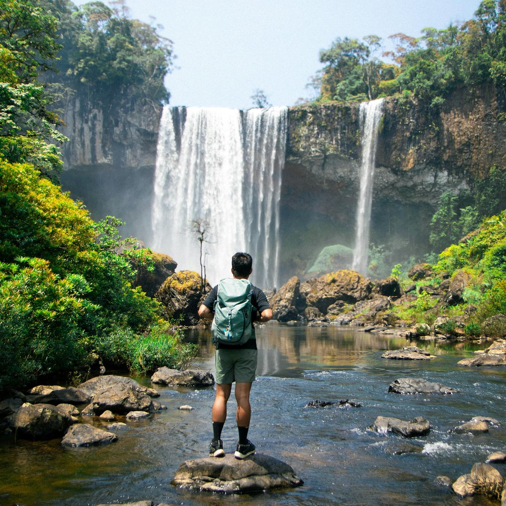 Adventurous hiker enjoying a mesmerizing waterfall in Kon Tum, Vietnam.